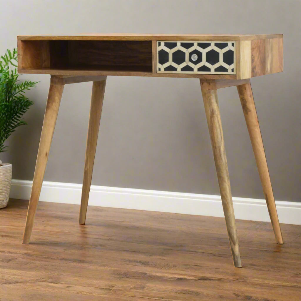 Front angled view of the Honeycomb Bone Inlay Desk, showcasing the honeycomb pattern on the drawer, the open slot, four Nordic style legs, and an ornamental plant in the background.