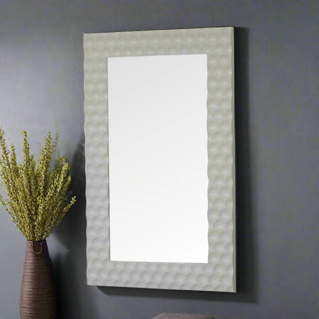 Side view of the Honeycomb Mirror standing as a leaning mirror on a grey wall, with a decorative plant beside it.