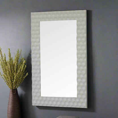 Side view of the Honeycomb Mirror standing as a leaning mirror on a grey wall, with a decorative plant beside it.