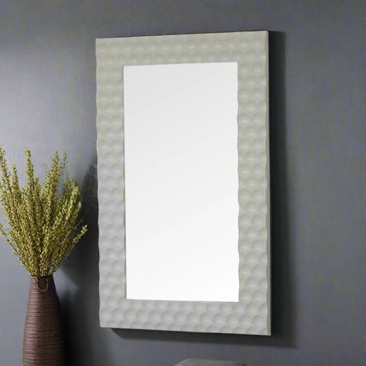 Side view of the Honeycomb Mirror standing as a leaning mirror on a grey wall, with a decorative plant beside it.