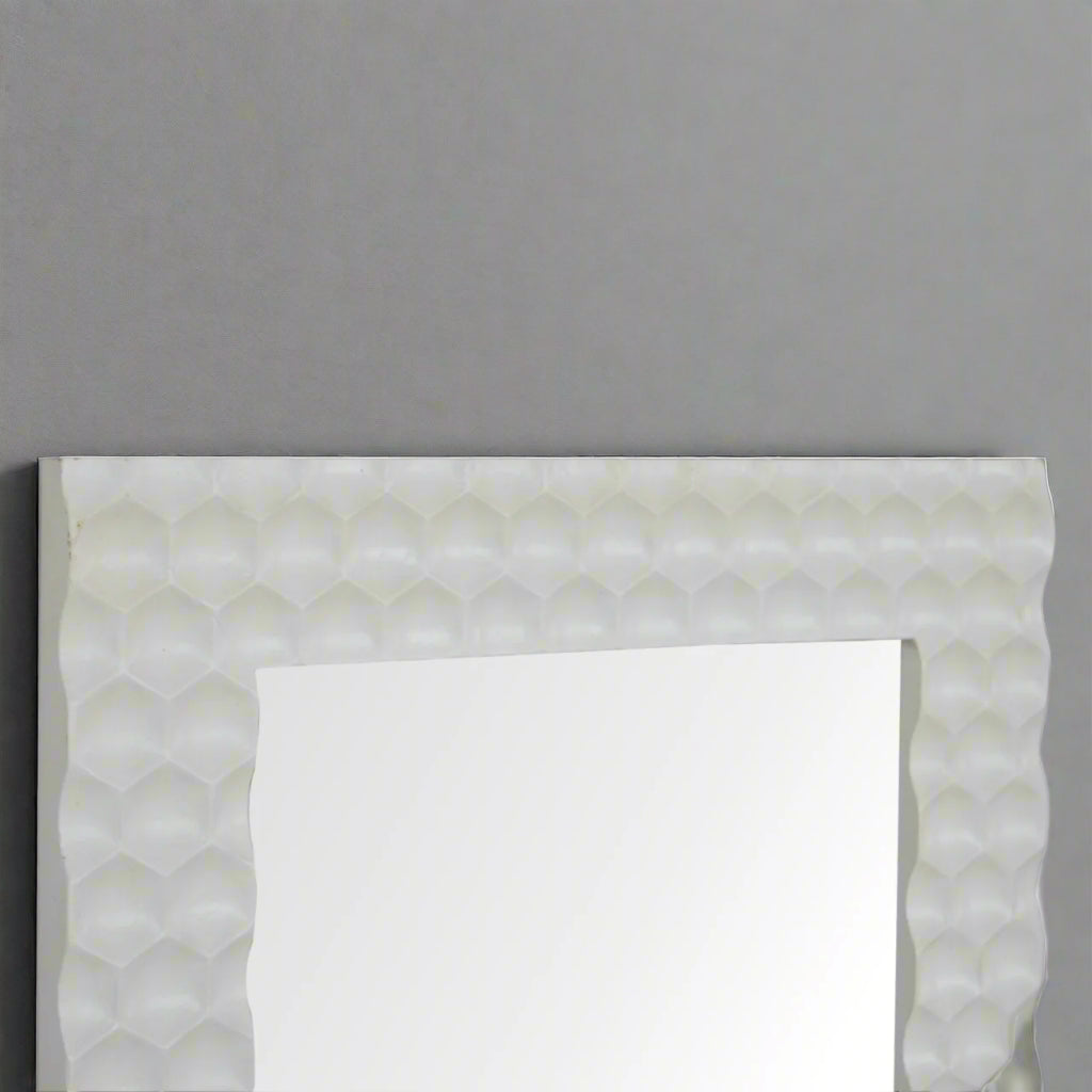 Upper half view of the Honeycomb Mirror, showing the reflection and the detailed hand-carved white honeycomb frame against a grey wall.