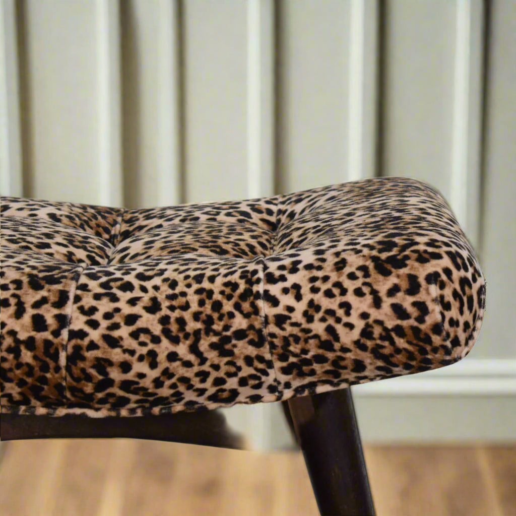 Elevated view of the left edge of the Leopard Print Curve Stool's seat, highlighting the velvet upholstery and a section of its legs.
