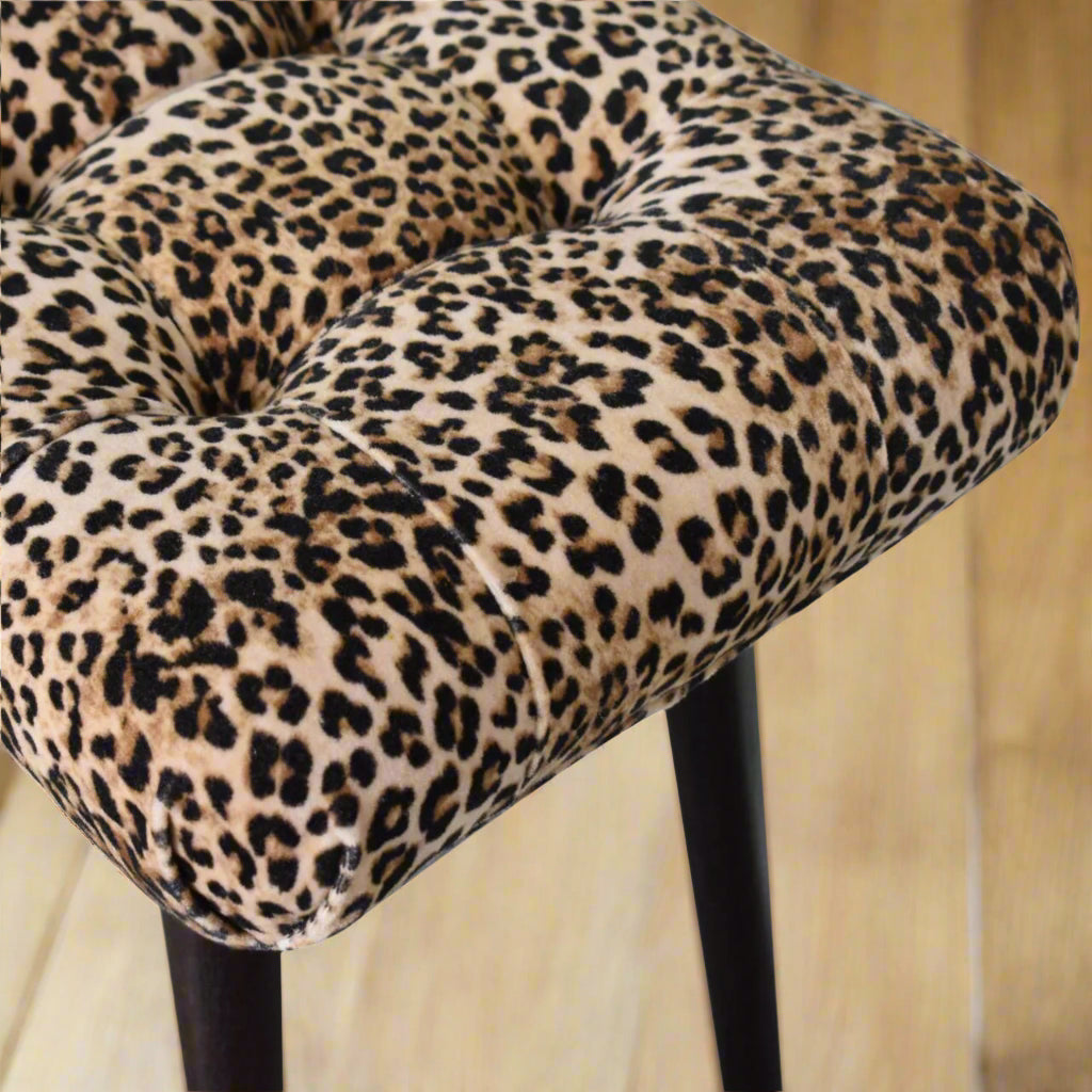 Top-down view of the Leopard Print Curve Stool's seat, showcasing the vibrant leopard print and classic deep button style.