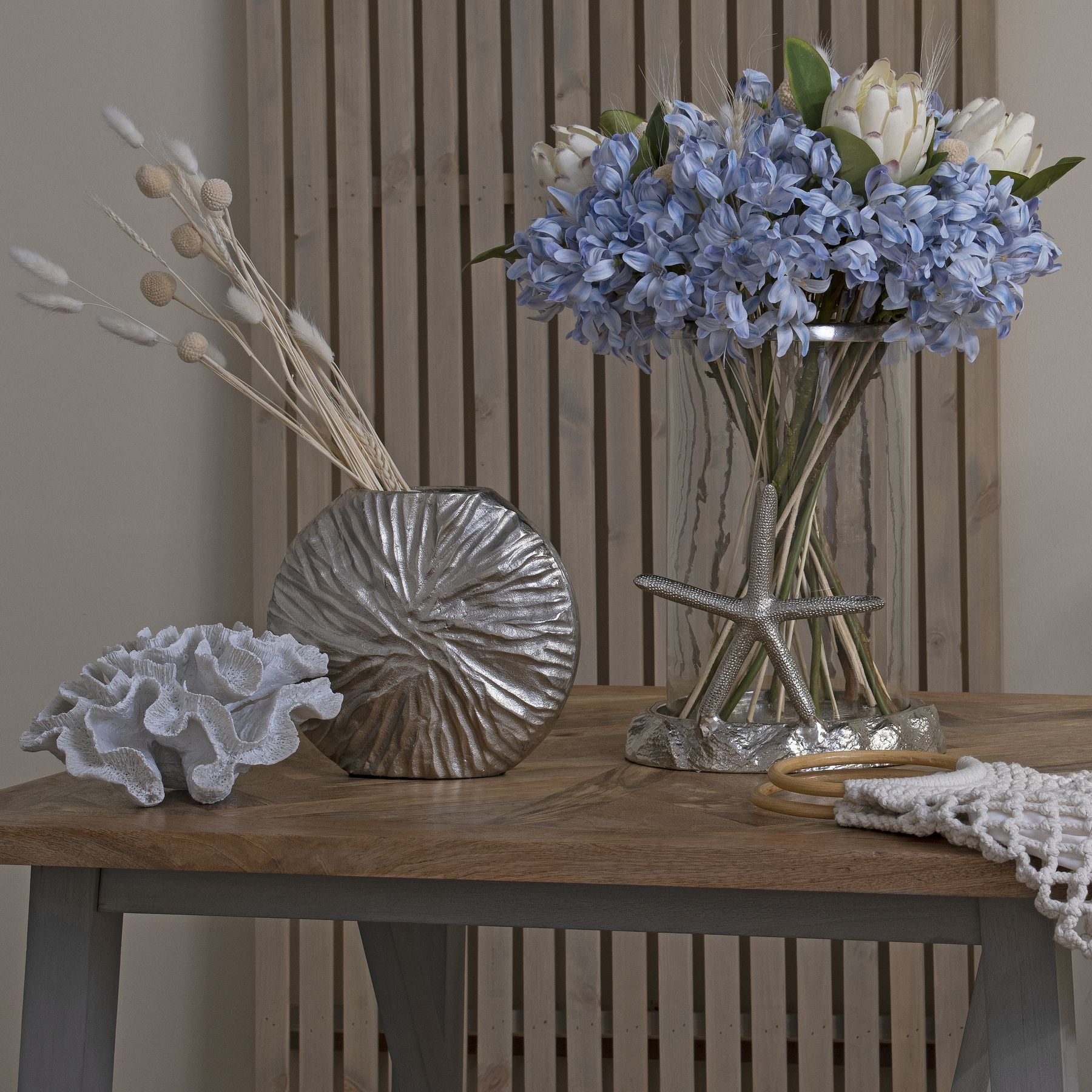 Closer view of a bunch of light blue agapanthus in a clear vase on a table styled with decorative items.