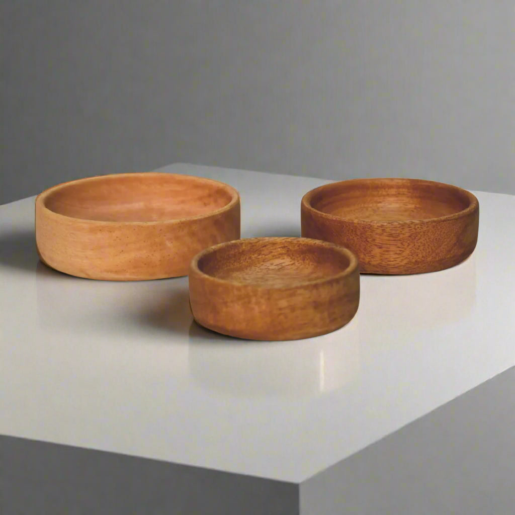 Set of three mango wood bowls side by side on a white surface – ideal for serving.
