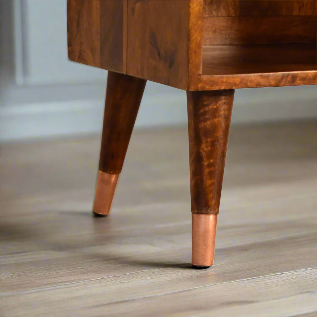 A zoomed-in view of the Nordic style feet of the Manila Copper 1 Drawer Bedside Table, emphasizing their brass caps.