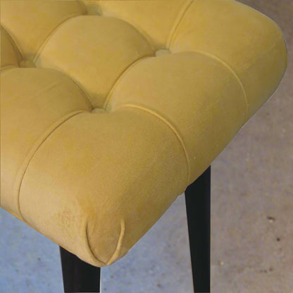 A zoomed-in aerial view of the mini mustard velvet curve stool, highlighting the luxurious texture and detail of the mustard velvet fabric.