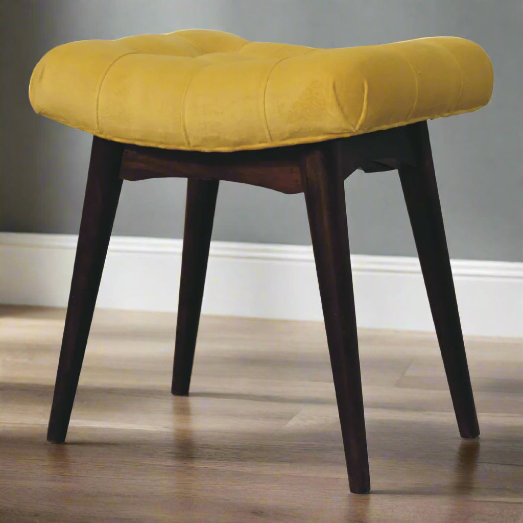 Angled view of the front side of the mini mustard velvet curve stool, showcasing all four Nordic style feet and the complete stool design.