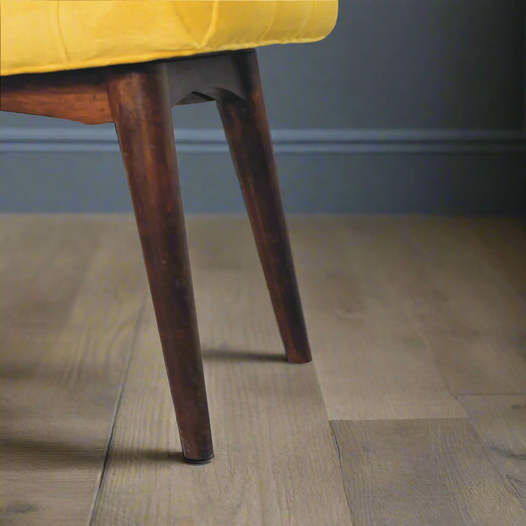 A clear view of the Nordic style legs of the mini mustard velvet curve stool, showcasing their design and walnut finish.