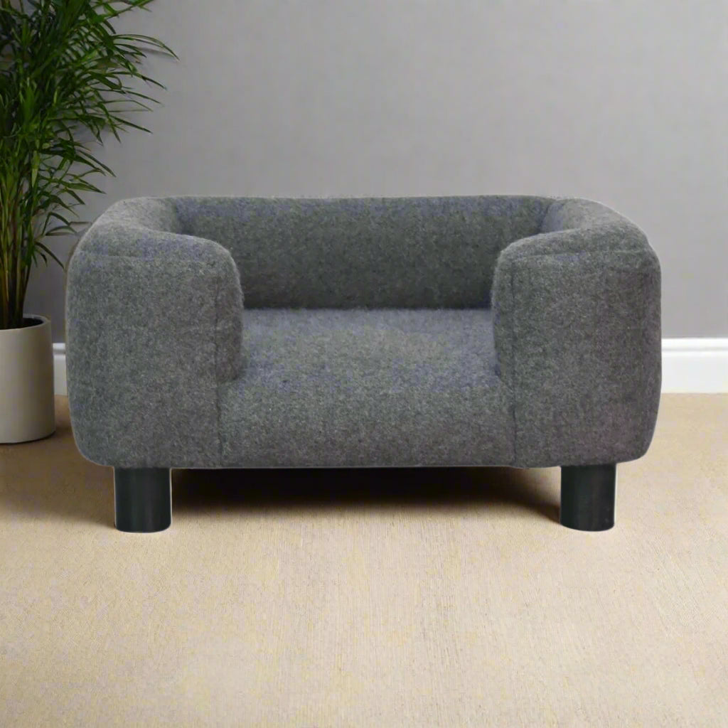 Front view of the battleship grey mini pet sofa bed with surrounding greenery.