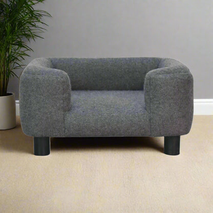 Front view of the battleship grey mini pet sofa bed with surrounding greenery.