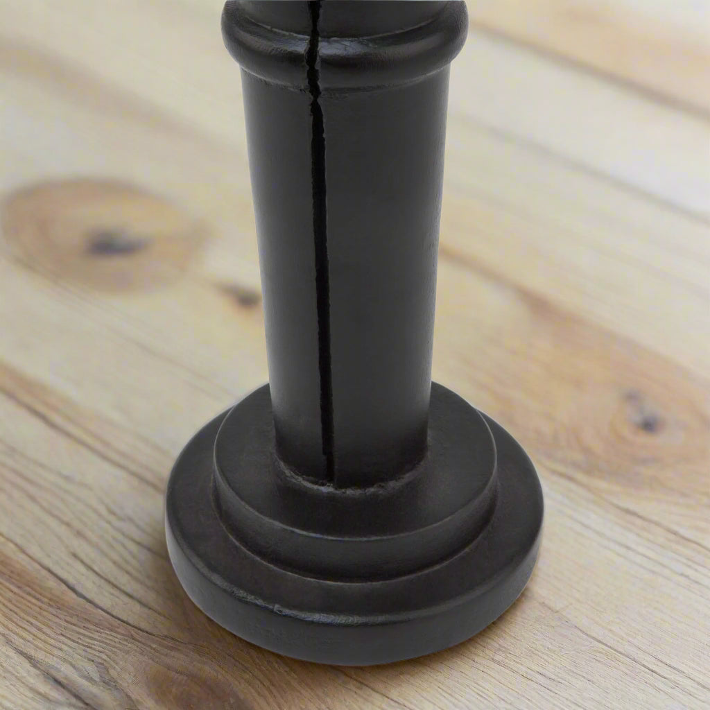 Close-up of the sturdy, rounded base of a minimalist black wooden large nutcracker decoration.