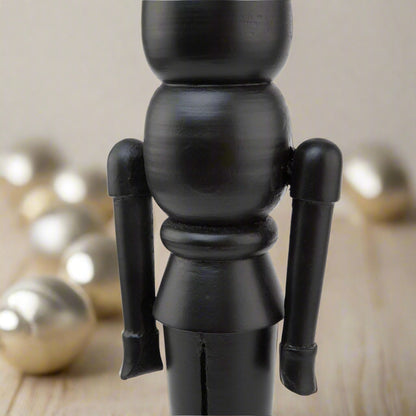 Detailed view of the arms and torso of a minimalist black wooden large nutcracker decoration, highlighting the smooth finish.
