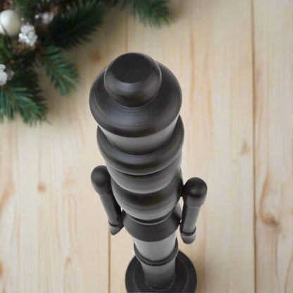 Close-up of the sculpted head and crown of a minimalist black wooden large nutcracker decoration.