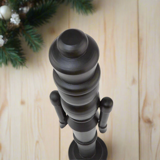 Close-up of the sculpted head and crown of a minimalist black wooden large nutcracker decoration.