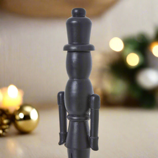 Close-up of the detailed head and top of a minimalist black wooden nutcracker decoration, showing its modern design.