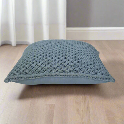 Side view of a Myra blue cushion placed horizontally on a table, illustrating the generous size and plumpness of its filling.