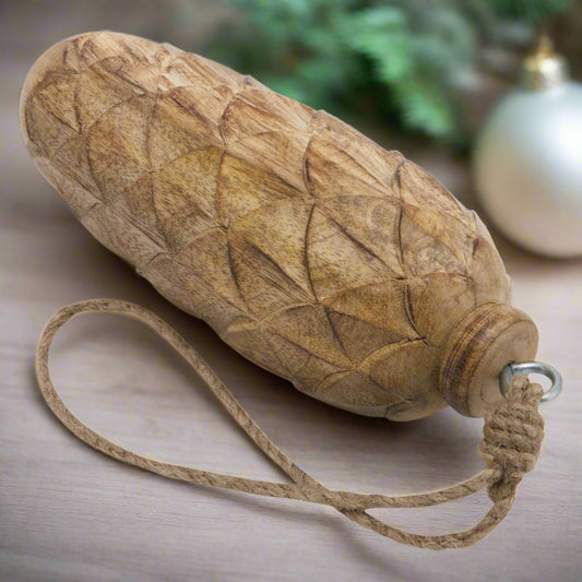 Close-up of a natural large wooden pine cone bauble, showing the detailed carved texture and a natural rope loop for hanging.