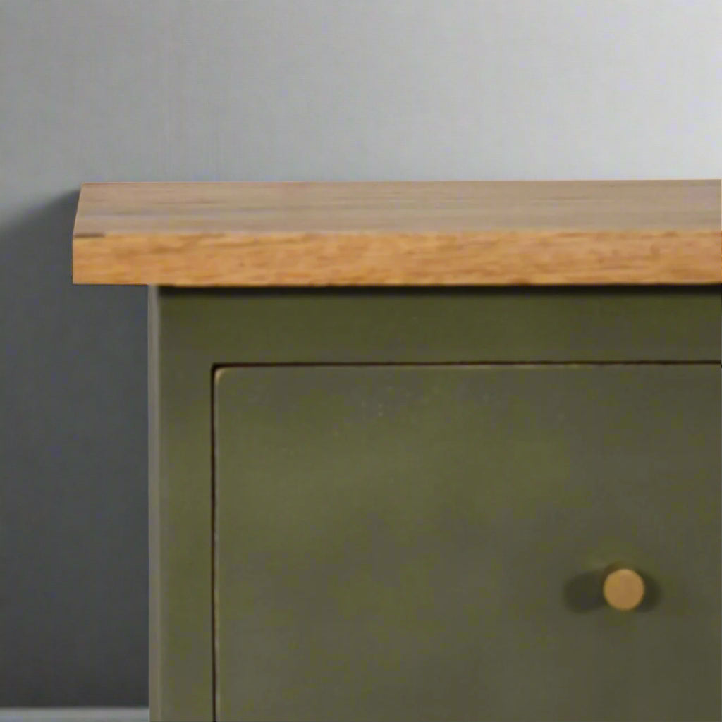 A closer look at the right edge of the olive hand-painted bedside table, focusing on the shiny drawer knob and the upper wooden surface.