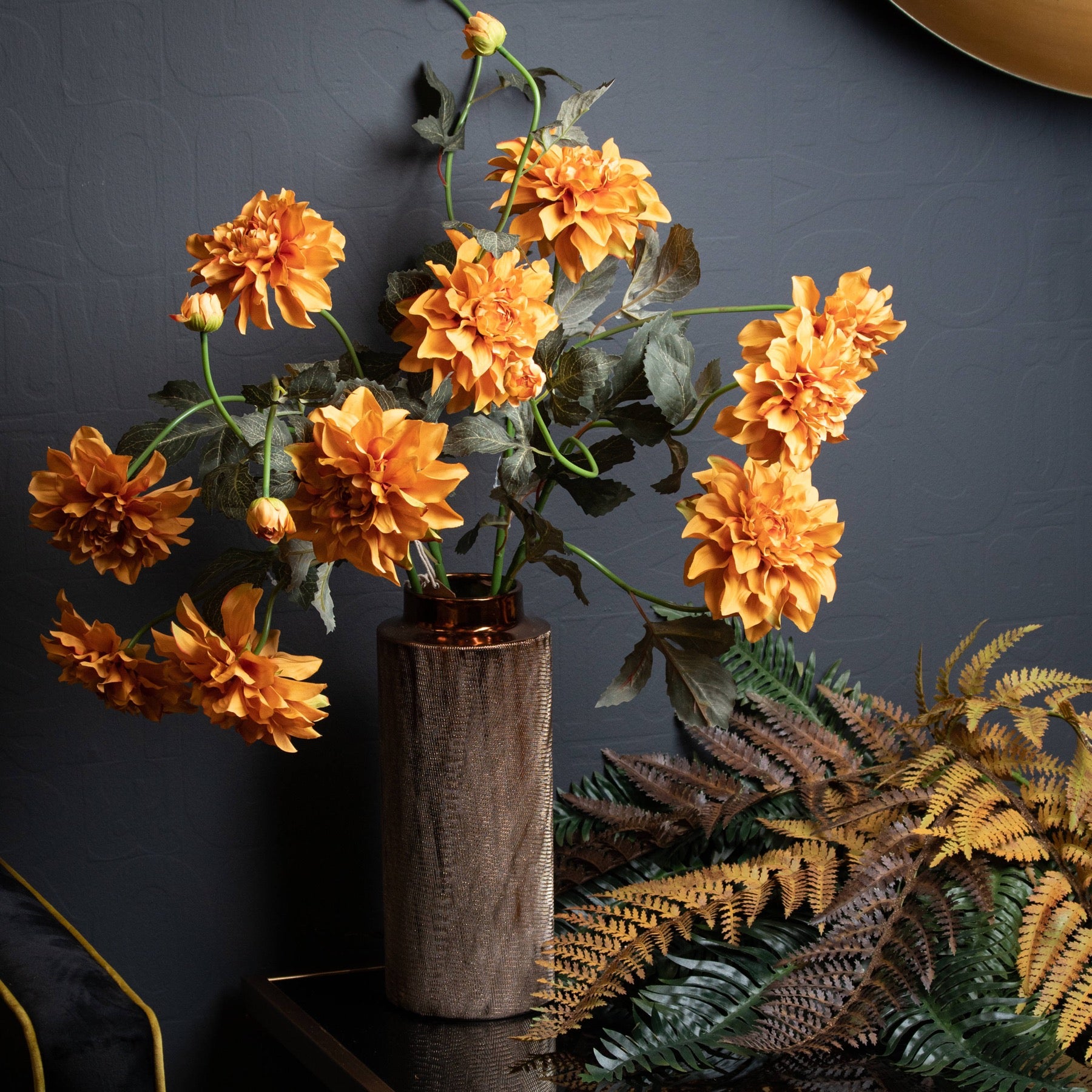 Artificial orange dahlia spray arranged in a tall rustic vase with realistic detail