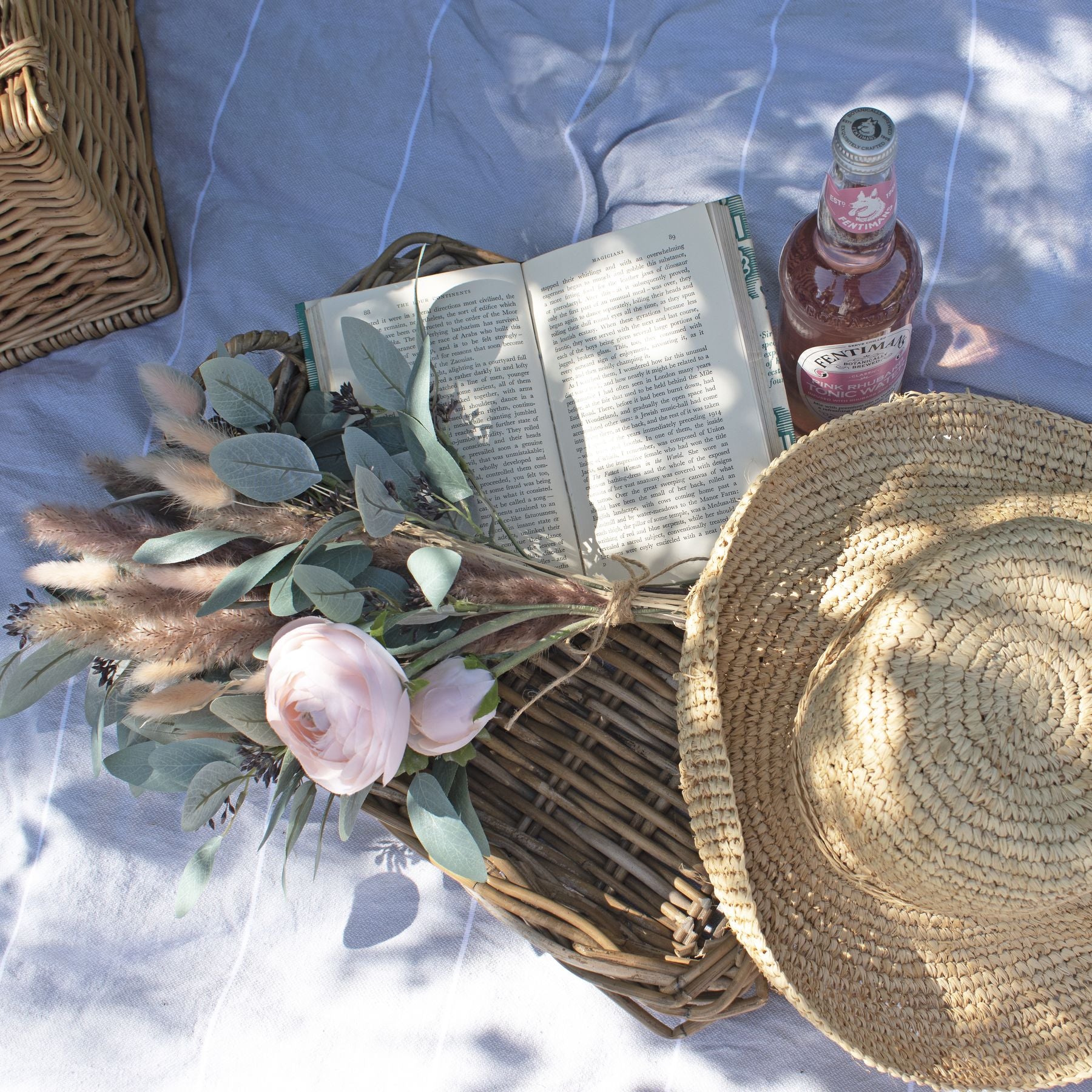 Styled flat lay of pastel pink ranunculus flowers with a sunhat and accessories – a dreamy seasonal decor inspiration.
