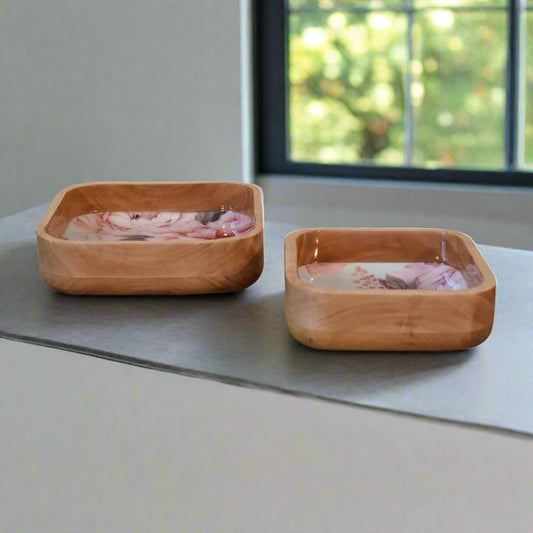 Two Pink Floral Square Bowls placed side by side, showing a glimpse of the pink floral design inside and the natural mango wood grain on the outside, near a window.