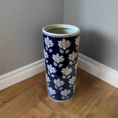 Purple Flamingo tall blue and white floral pattern ceramic umbrella or stick stand with a glossy finish, standing in a room corner on a wooden floor.