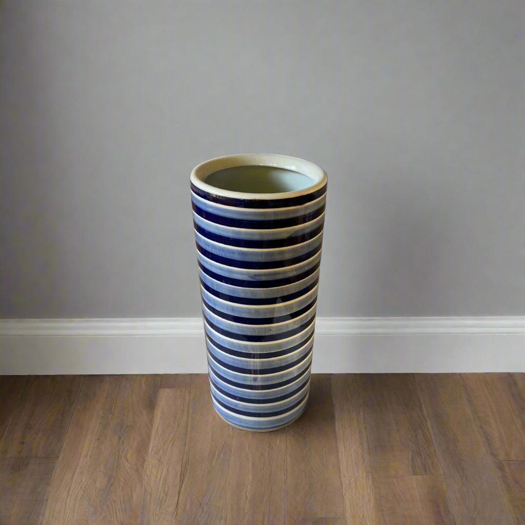 Purple Flamingo tall blue and white striped ceramic umbrella or stick stand with a glossy finish, shown in a room.