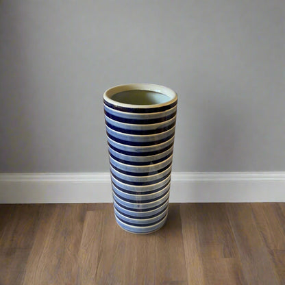 Purple Flamingo tall blue and white striped ceramic umbrella or stick stand with a glossy finish, shown in a room.
