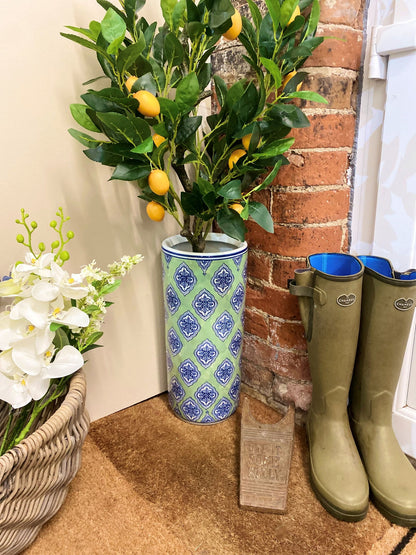 Purple Flamingo green and blue diamond print ceramic umbrella stand with a lemon tree plant, styled in a hallway entrance with wellington boots.