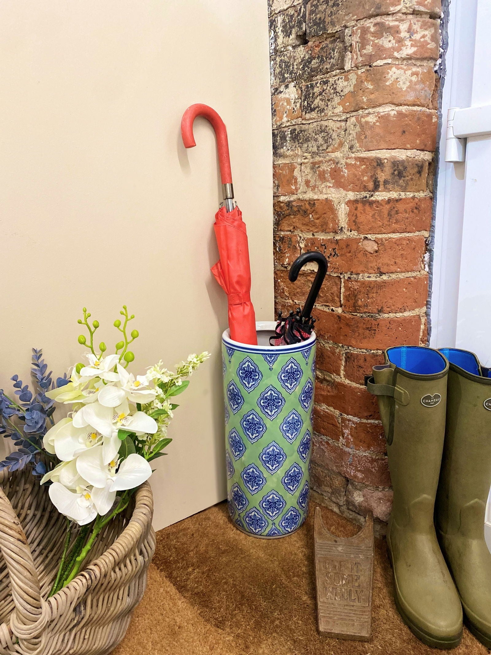 Purple Flamingo green and blue diamond print ceramic umbrella stand holding two umbrellas, perfect for a tidy hallway.