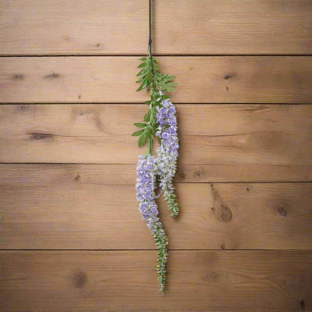 Aerial shot of one purple wisteria stem on the wooden surface.