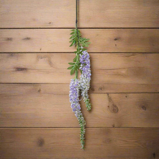 Aerial shot of one purple wisteria stem on the wooden surface.