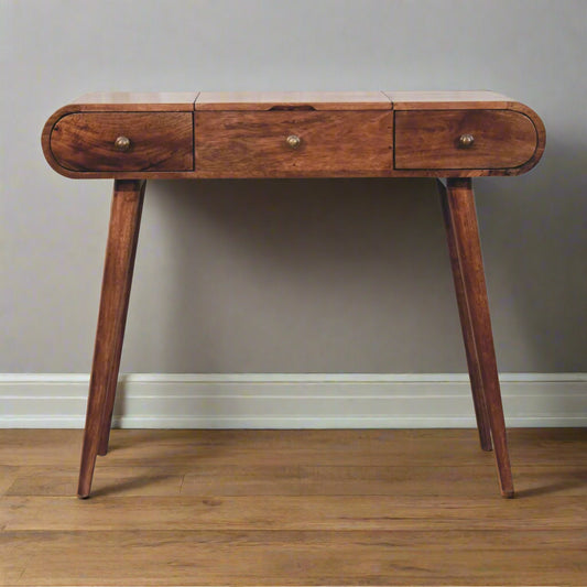 Front view of the rounded dressing table with honey caramel finish showing Nordic legs and closed drawers.
