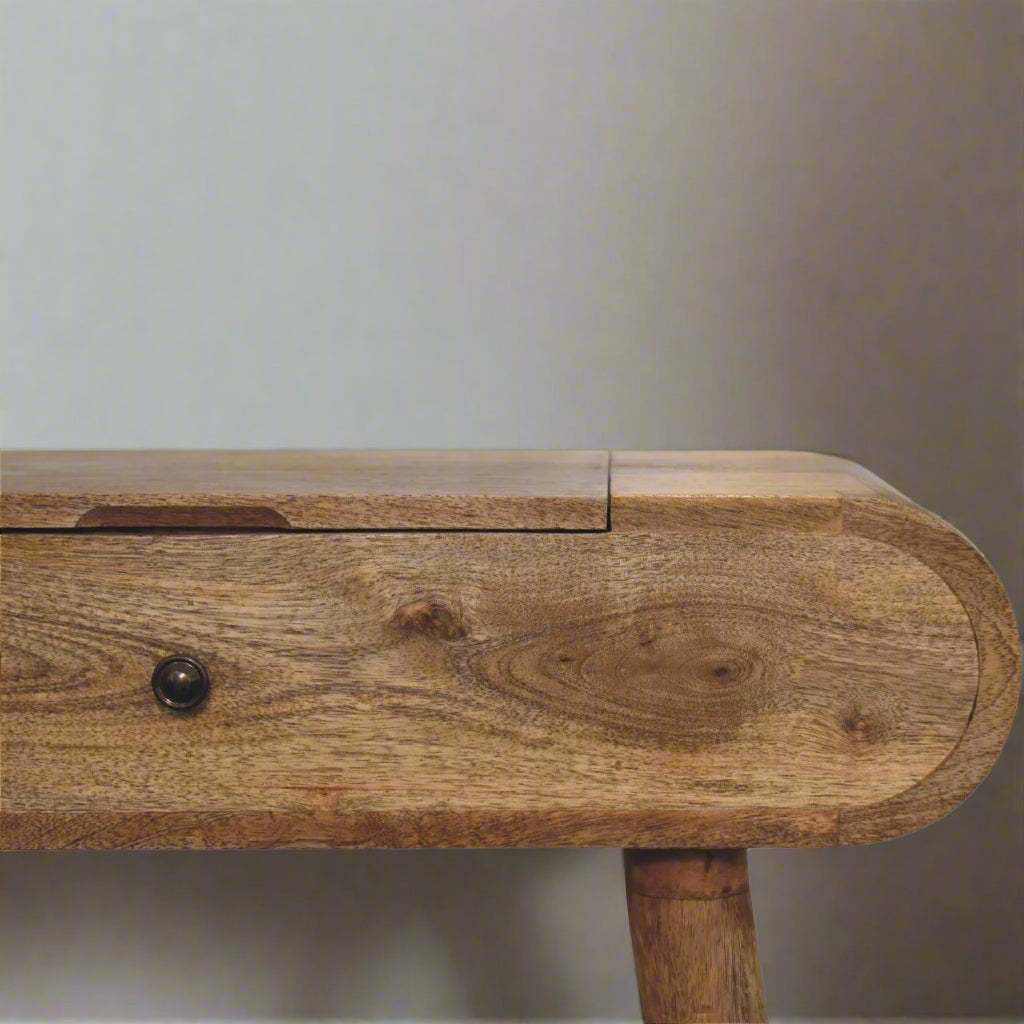Close view of right side of rounded mini dressing table, with oak-ish finish, showcasing the smooth rounded edge and pull handle.