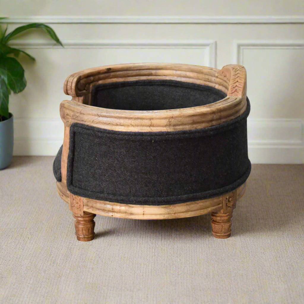 side view of the elevated pet bed, highlighting the curved wooden back and decorative plant in the background.