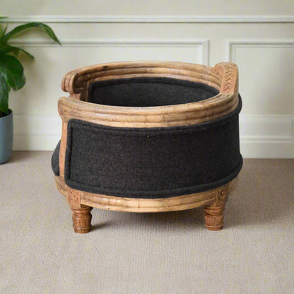 side view of the elevated pet bed, highlighting the curved wooden back and decorative plant in the background.