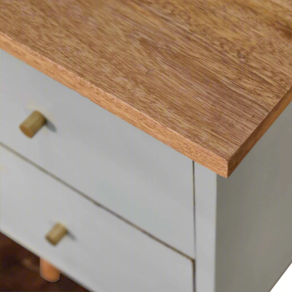 A closer look at the left edge of the sky blue hand-painted bedside table, focusing on the shiny drawer knob and the upper wooden surface.