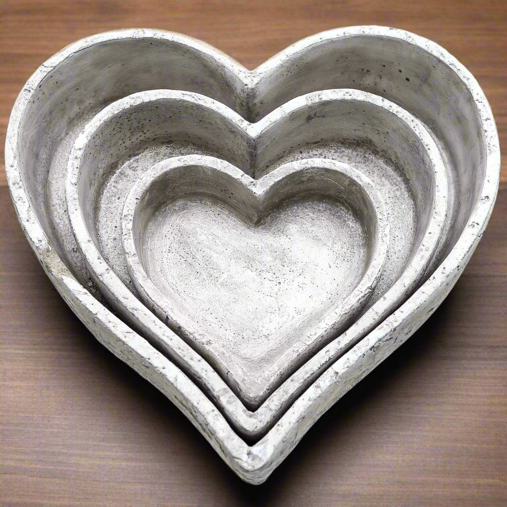 Close-up of stacked heart-shaped grey ceramic dishes showing their textured stone surface and minimalist handcrafted design.