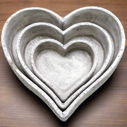 Close-up of stacked heart-shaped grey ceramic dishes showing their textured stone surface and minimalist handcrafted design.