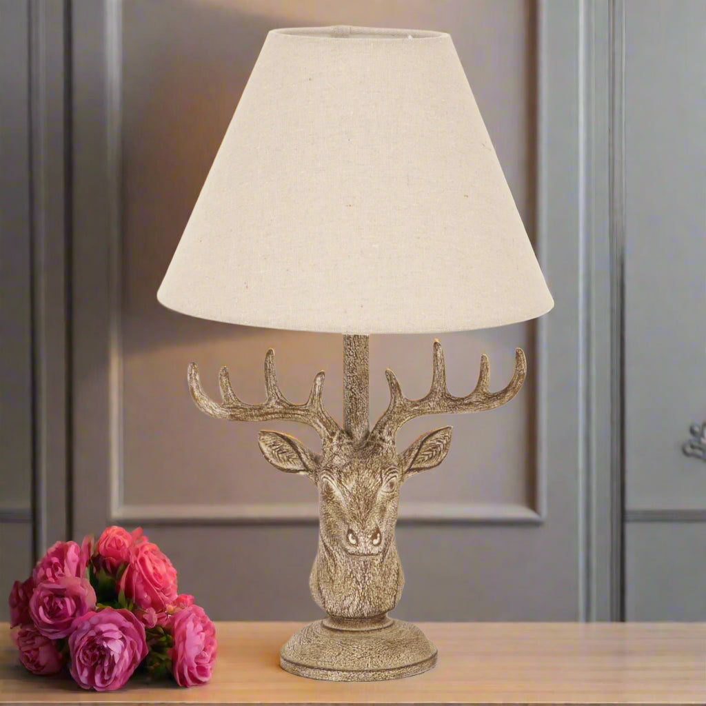 Stag head table lamp with linen shade – full view showing sculptural base and neutral-toned shade, available at Purple Flamingo UK