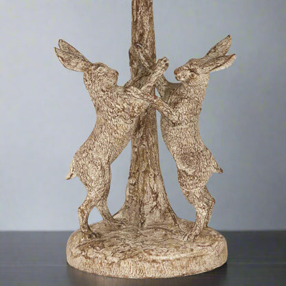 Close-up of the lamp’s base showing the detailed marching hares in a stonewashed finish.