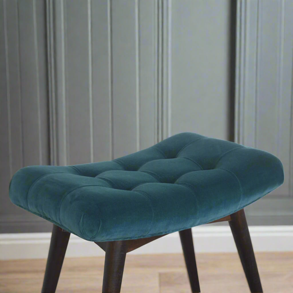 Elevated view of the teal velvet curve stool, showcasing the entire seating area, its distinctive deep button pattern, and a visible section of its legs.