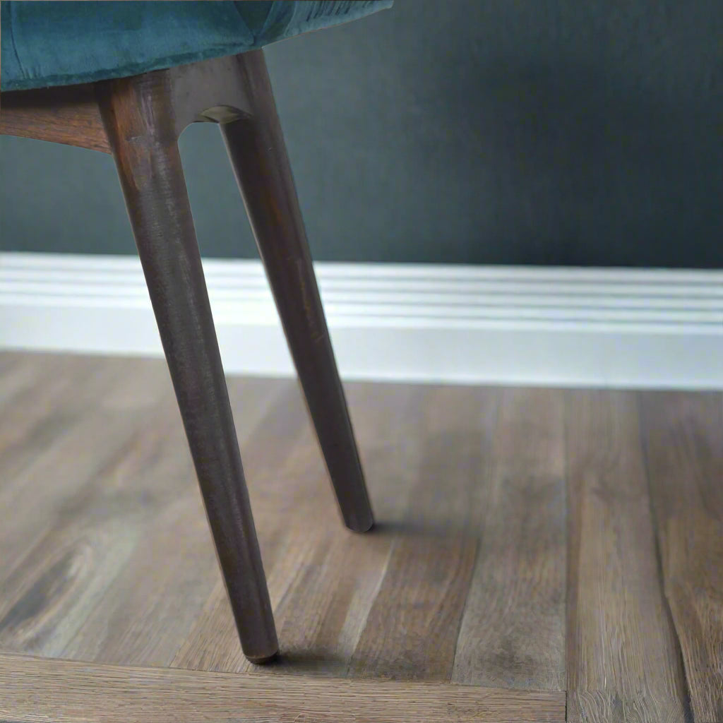 Close-up focus on the left Nordic style legs of the teal velvet curve stool, highlighting their design and walnut finish.
