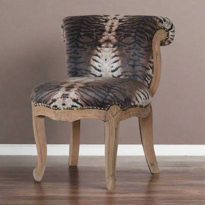 Front view of the tiger print velvet chair showing the curved back rest, carved wooden legs, and studded trim along the frame