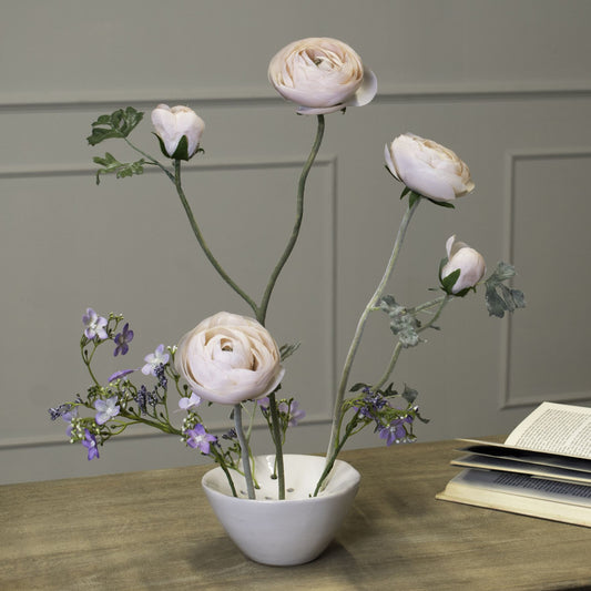 White ceramic flower frog vase styled with flowers on a wooden surface.
