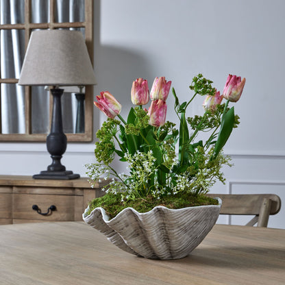 White Gypsophila and pink tulips styled in a decorative shell pot on a dining table. For spring or summer styling, from Purple Flamingo.