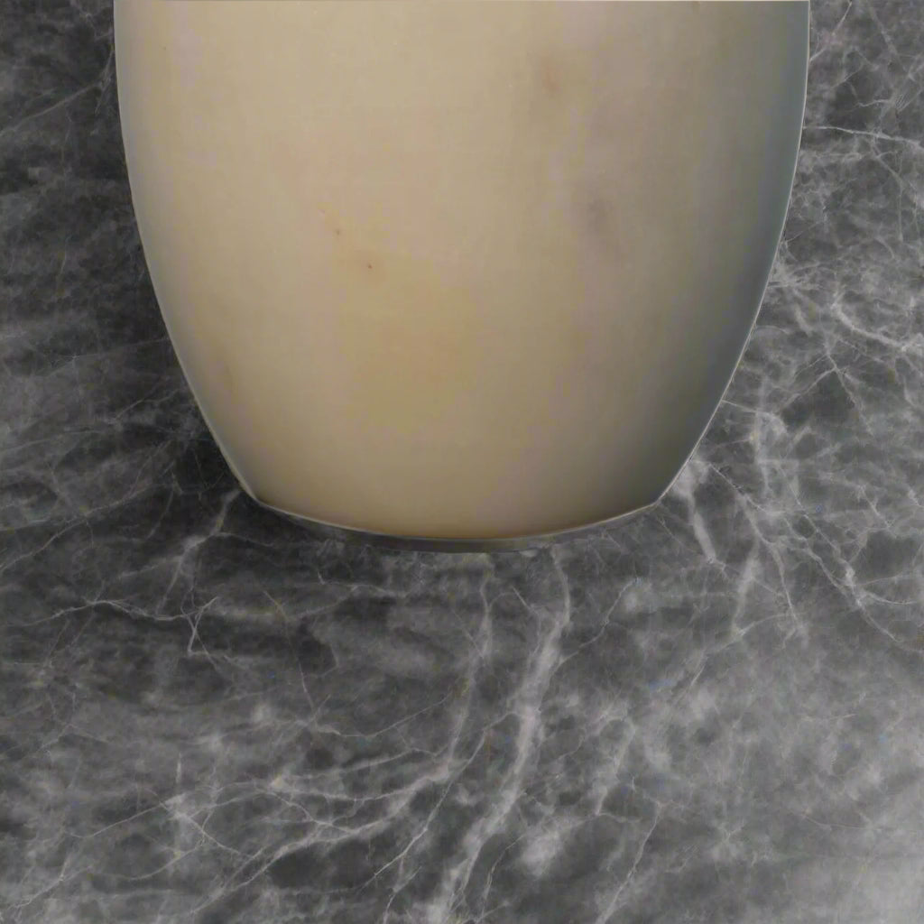 Close-up shot of the bottom edge of the white marble dispenser, showcasing its classic finish.