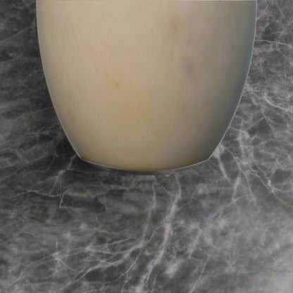 Close-up shot of the bottom edge of the white marble dispenser, showcasing its classic finish.