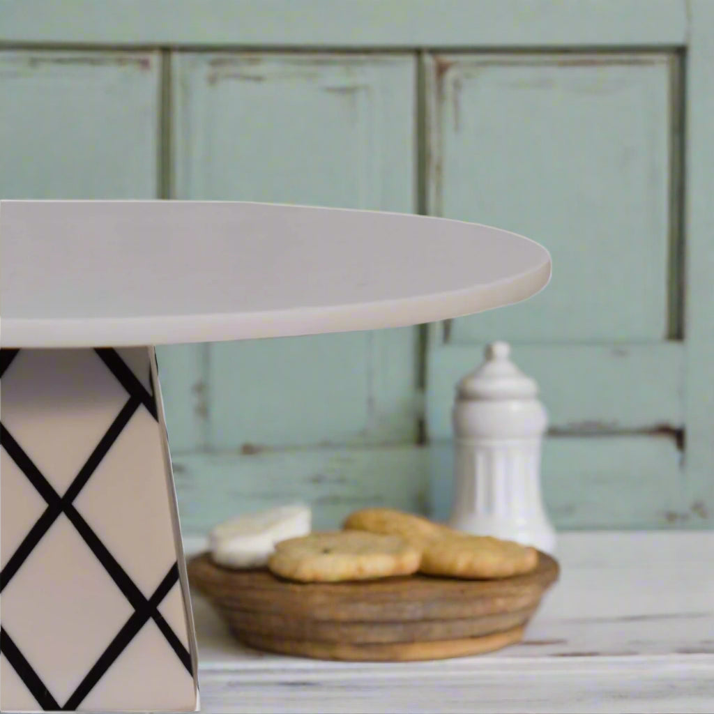 Angled view of the White Marble & Resin Cake Stand/Platter with muffins and baked goods in the background, suitable for serving or home decor.